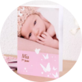 An adorable CEWE photo book shows a baby with a cute headband. The name Mia is on the cover.